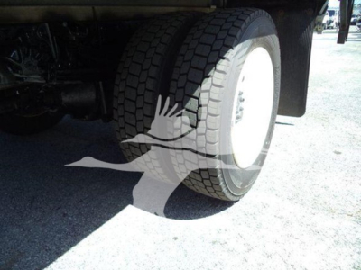 Truck rear wheel and tire assembly visible under a box truck, partial chassis and fender in view.