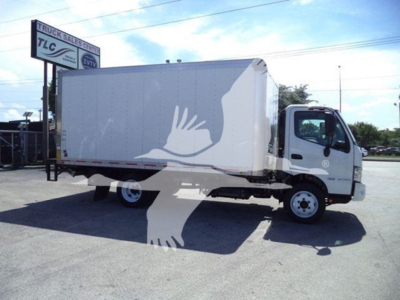 Box truck in side profile showing cargo box and cab with Hino emblem; white box body with a gray bird silhouette graphic; truck on a lot with signage in background.