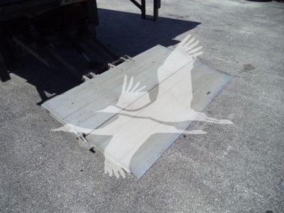 Truck loading ramp/platform with metal surface and hinge attachments, viewed from top-left angle.
