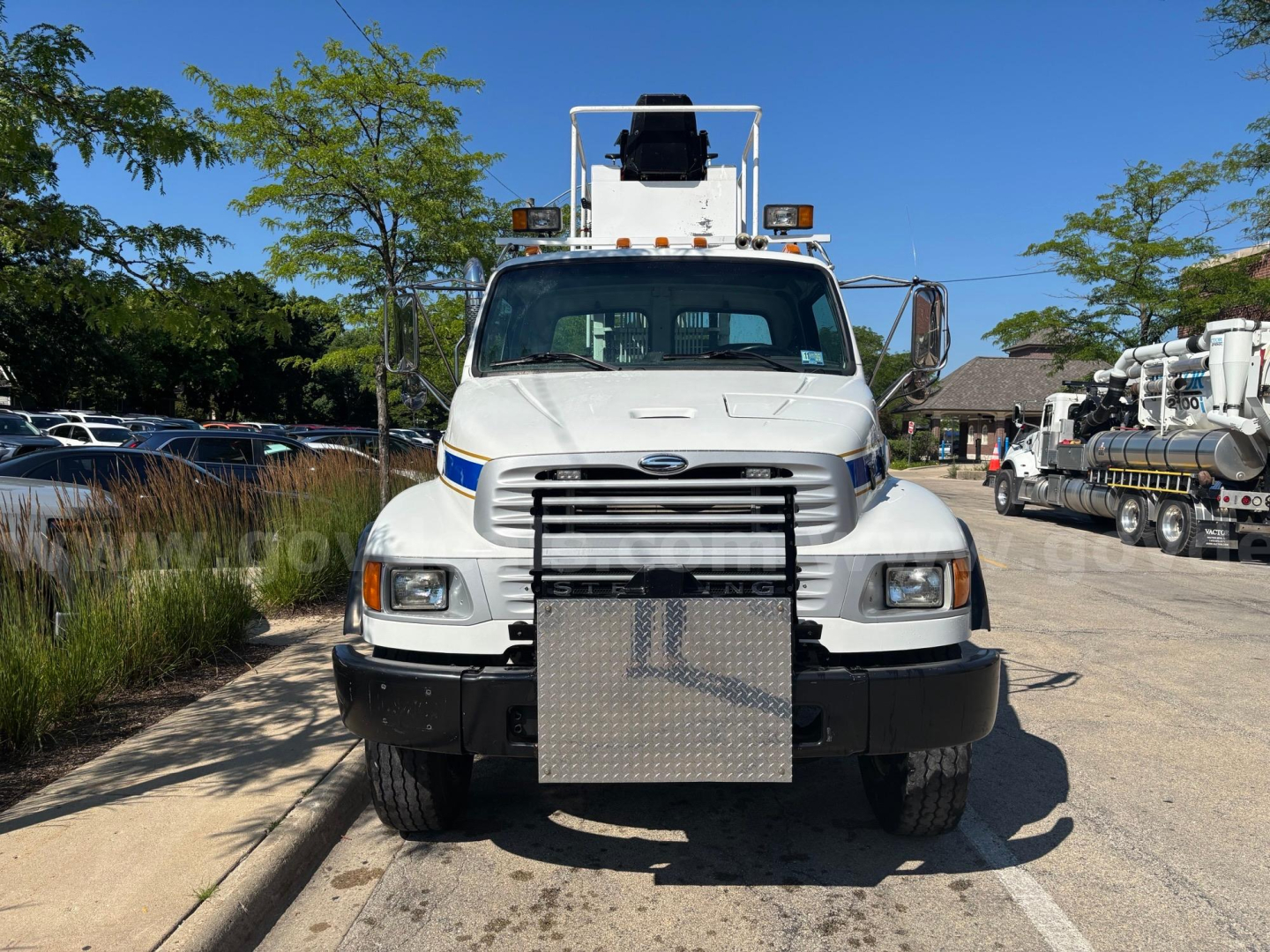 Front view of a white 2002 Sterling truck with a large steel bumper, grapple equipment, and grille, in a dealership lot.