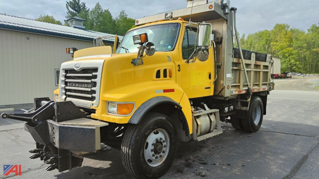 Dump truck with front plow and dump bed showing Sterling L8500 badge and yellow cab in-service.
