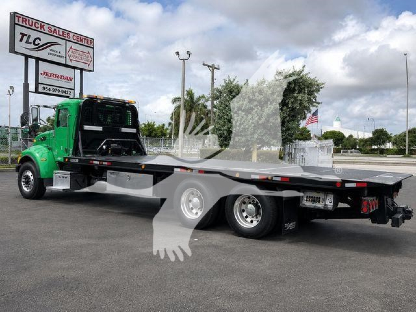 Peterbilt 348 rollback tow truck in green and black, flatbed with dual rear axles, visible TLC Truck Sales Center sign in background, VIN 2NP3LJ0X9HM442113.