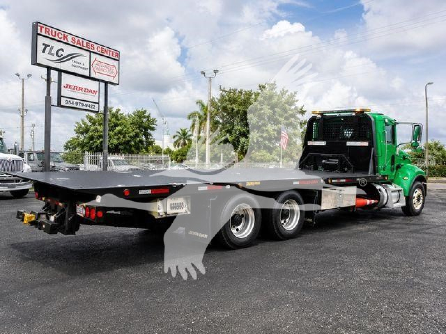 Peterbilt 348 rollback truck with green cab and flatbed trailer, side view showing low-profile deck and wheels.