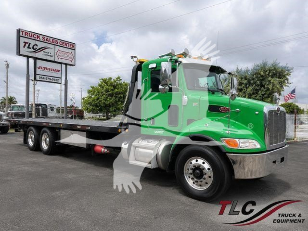 Peterbilt 348 rollback truck with a bright green cab and flatbed, side view, in a dealership lot.
