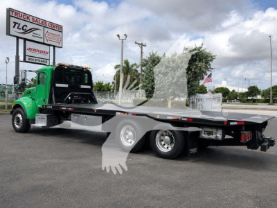 Peterbilt 348 rollback tow truck in green and black, flatbed with dual rear axles, visible TLC Truck Sales Center sign in background, VIN 2NP3LJ0X9HM442113.