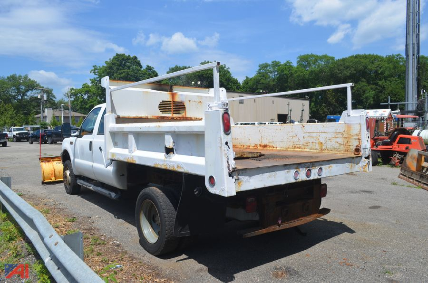 Dump truck bed of a white 2000 Ford F550 Super Duty from rear-left view showing rusty rack sides and tailgate in an equipment yard.