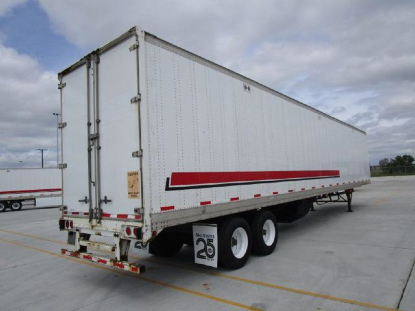 Stoughton van trailer (2014) side and rear view showing triple axle, white exterior, red reflective stripe, rear doors, and bumper with spare tag.