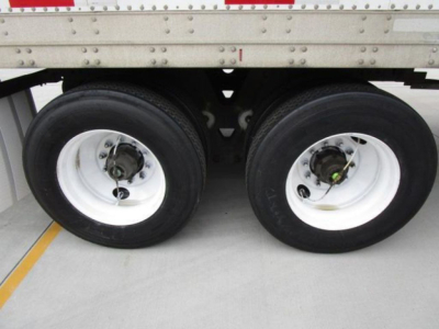Dual trailer wheels with white rims and black tires under a Stoughton van trailer, showing the axles and leaf spring components.