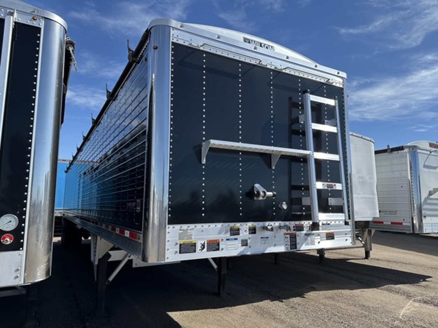 Wilson 42' air ride grain trailer with 79" sides, side access ladder, rear door, and reflective tape in a lot.