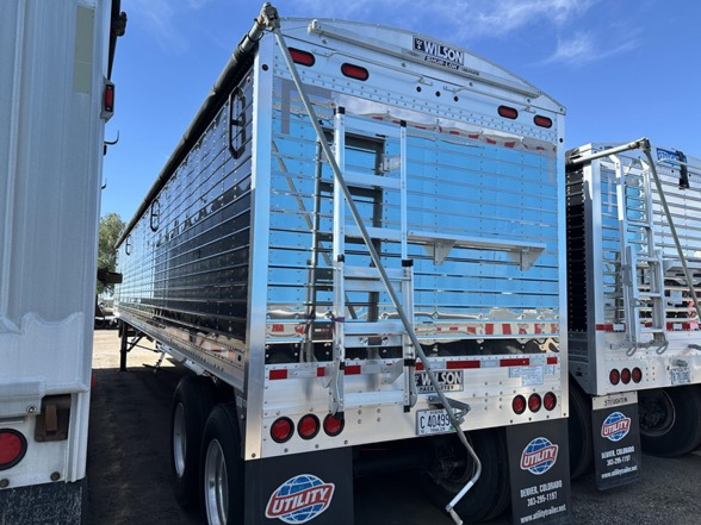 Trailer rear view showing Wilson grain trailer with 79-inch sides, aluminum body, dual rear doors, and multiple safety lights.