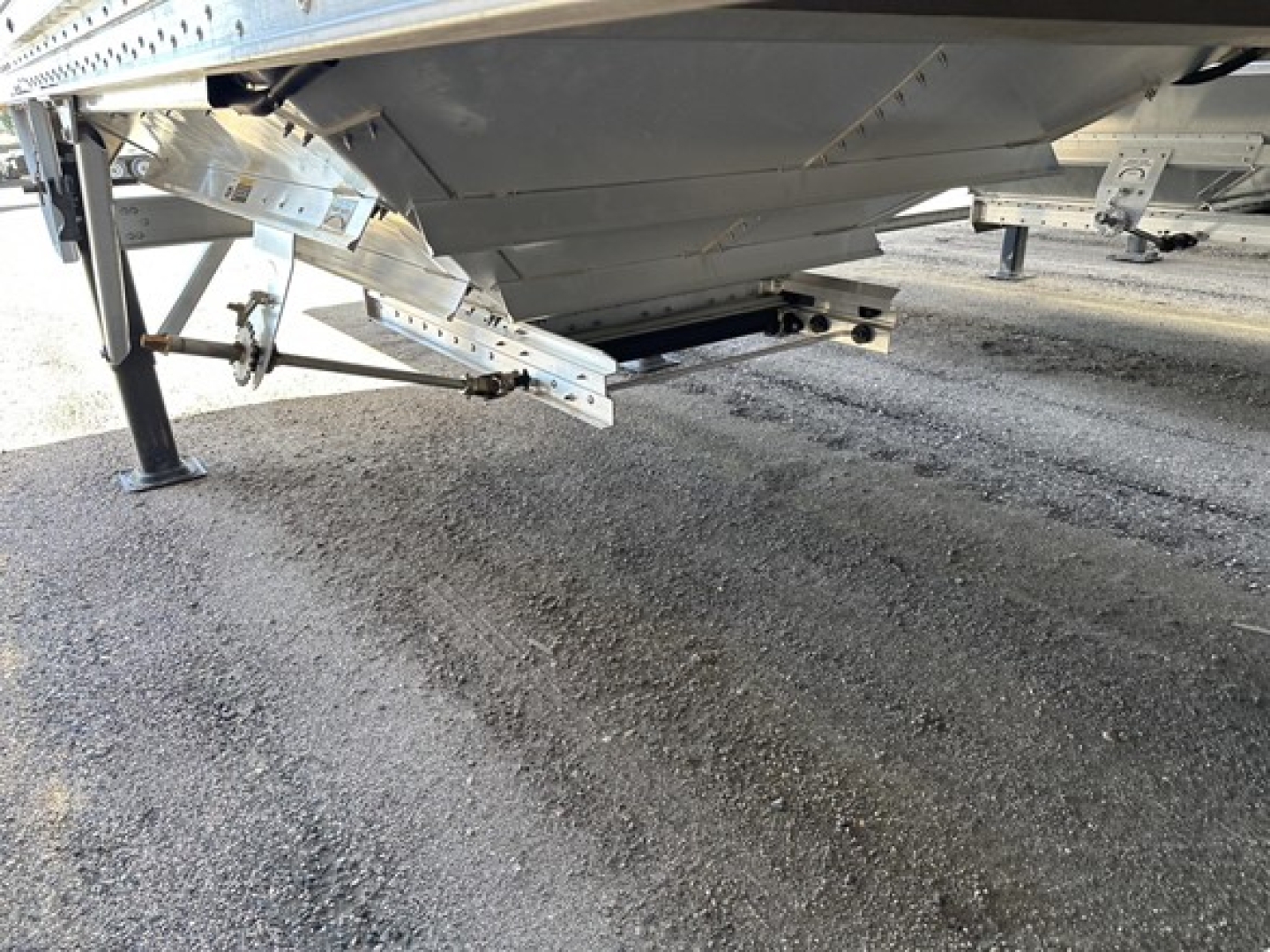 Trailer underside and support legs showing metal frame and drop-down support with light reflection on galvanized steel.