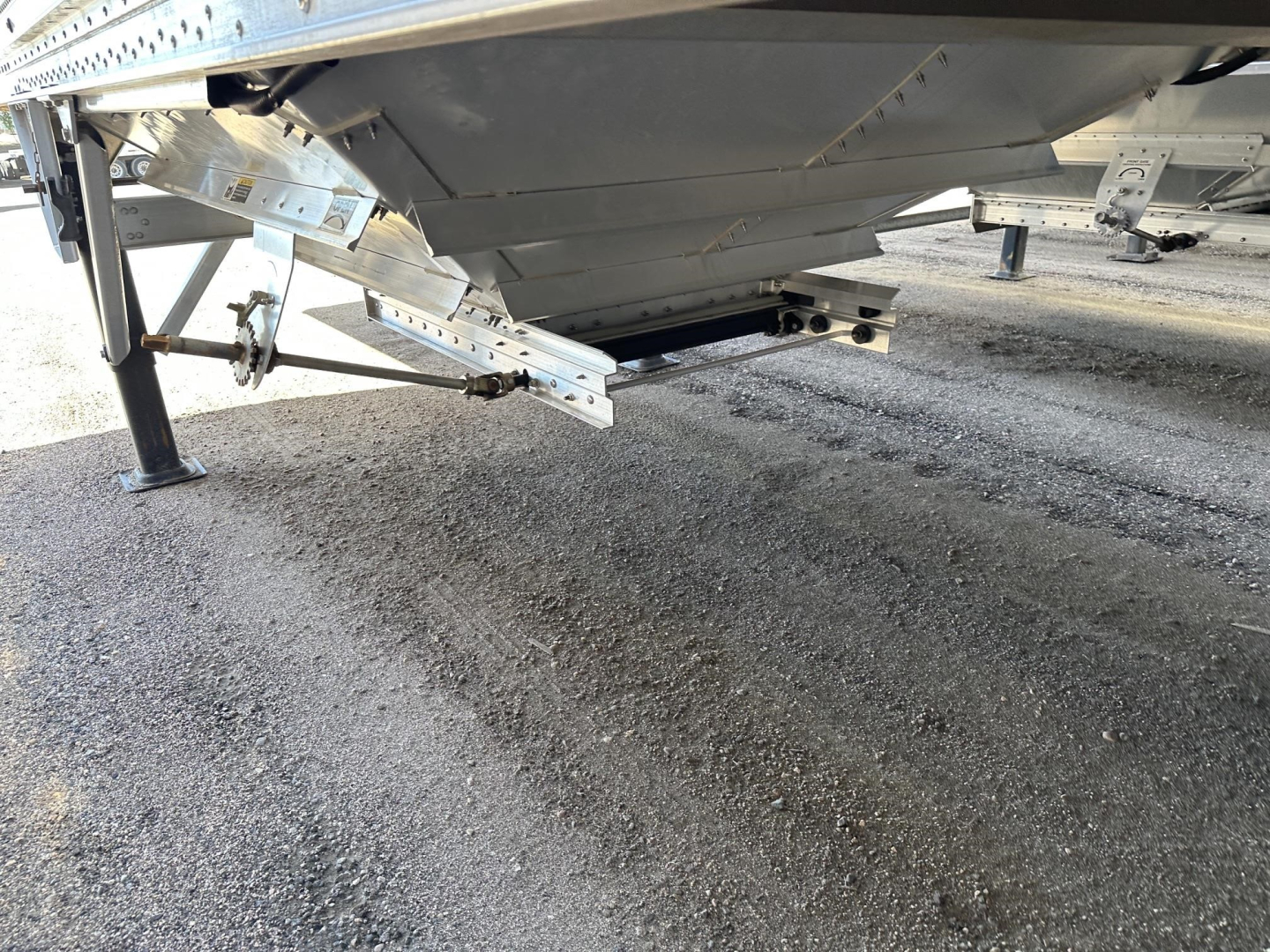 Trailer undercarriage showing aluminum frame and support legs with drilled side panels and hitch area.