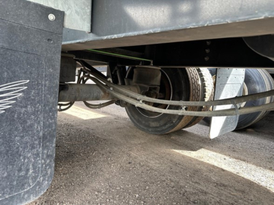 Trailer unde chassis view showing axle and suspension components under a 2019 Manac spread air steel flatbed.