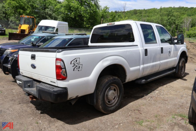 Ford F-250 Super Duty pickup truck rear-left view showing crew cab, bed decal, and dual rear wheels on a dirt lot.