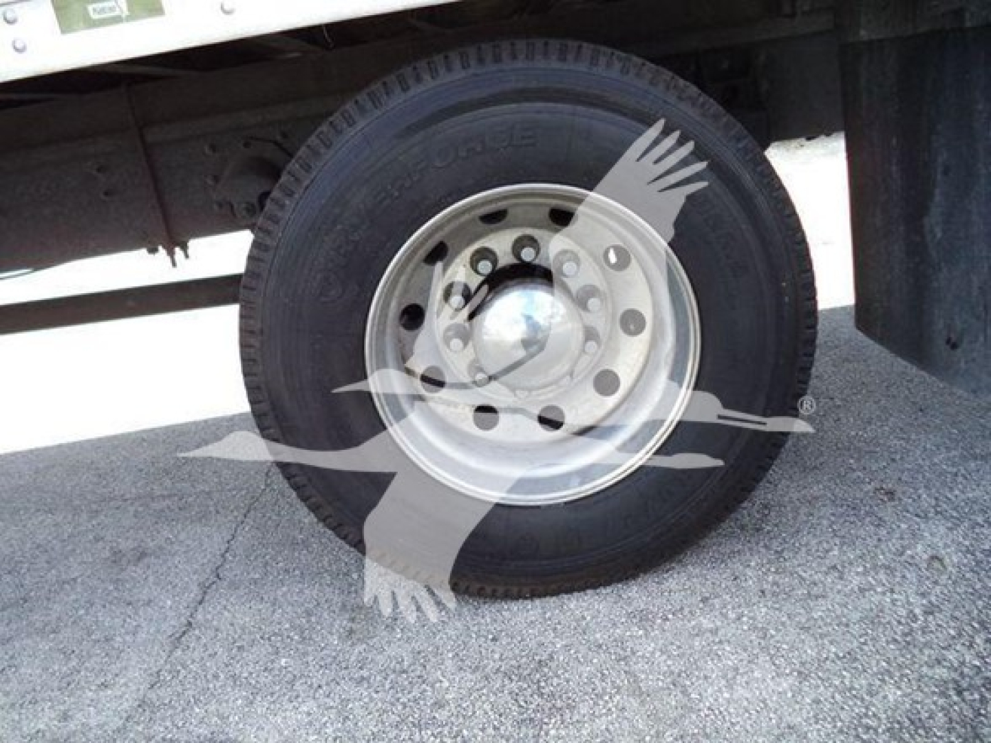 Wheel close-up showing tire and steel rim on Mack MD6 refrigerated truck with visible tread pattern and hub cap.