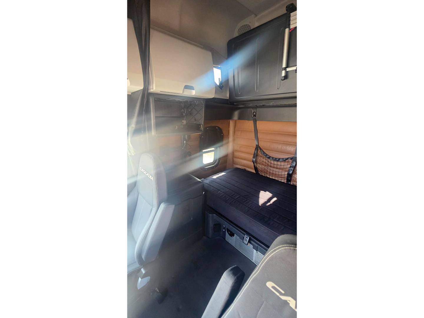 Truck interior view of a 2021 Freightliner Cascadia126 sleeper cab showing bunk area and cabin storage