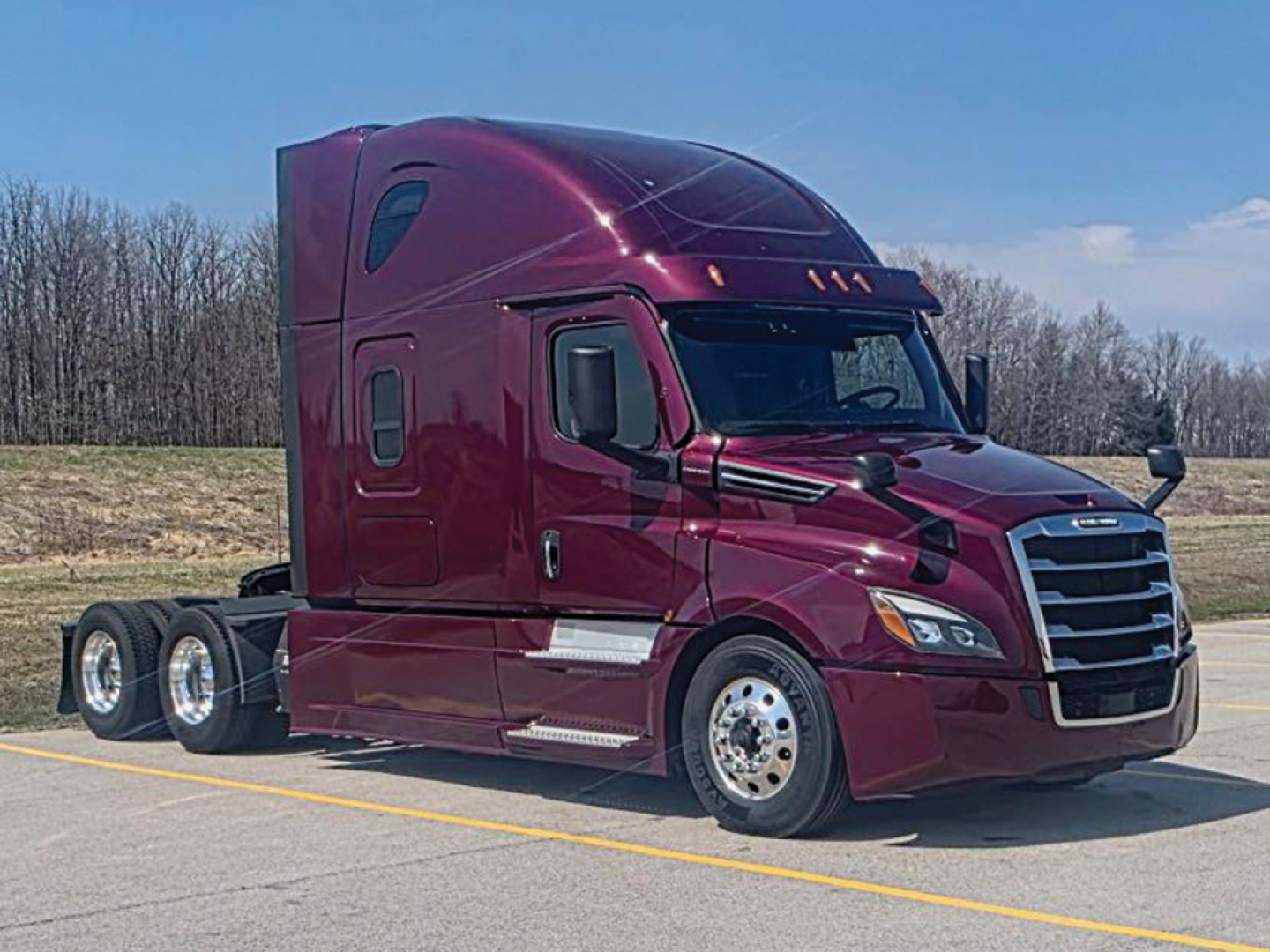 Conventional sleeper semi-truck tractor in maroon showing aerodynamic cab and dual rear axles.