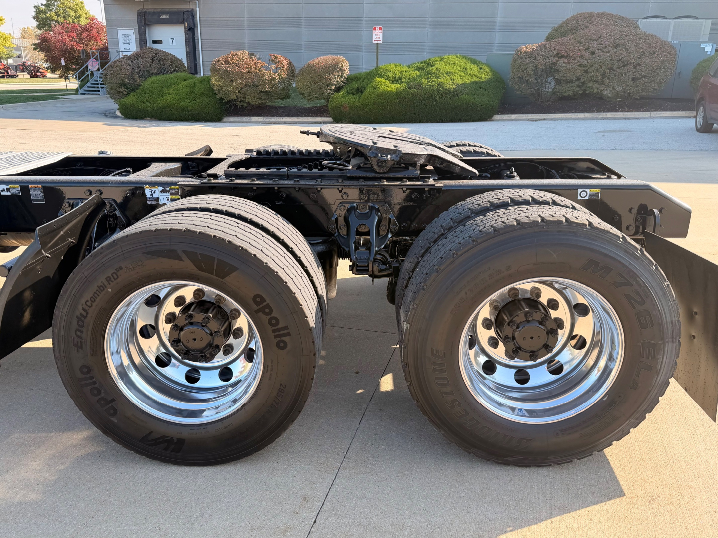 Kenworth T880 chassis side showing dual rear axles with large chrome wheels and tires; no cab visible, trailer hitch area and frame overhead.
