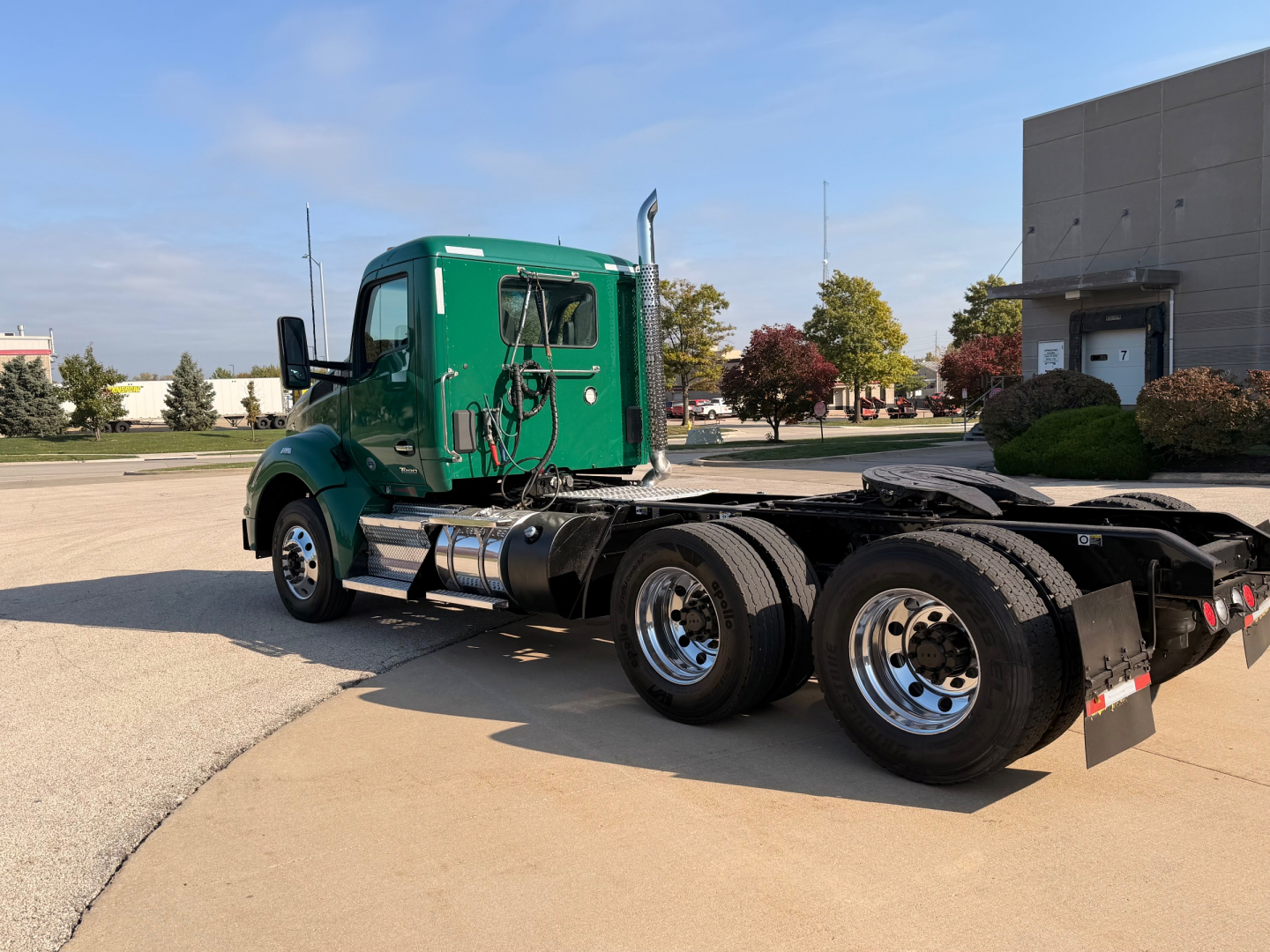 Kenworth T880 conventional daycab truck side view showing green cab and chassis with dual rear axles and fuel tanks.