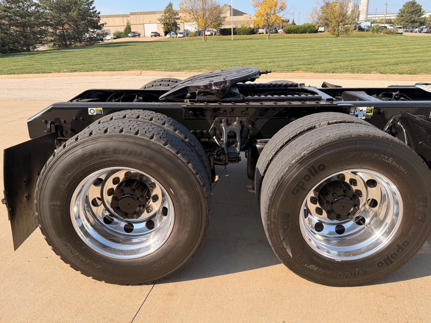 Kenworth T880 truck chassis showing dual rear axles with large chrome wheels and tires, frame rails, and fifth wheel coupling area.