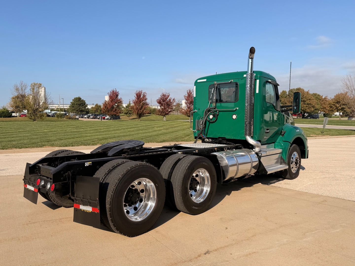 Kenworth T880 semi truck rear/side view showing green cab, dual rear axles, fuel tanks, and exhaust stack.