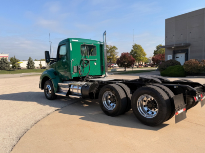 Kenworth T880 conventional daycab truck side view showing green cab and chassis with dual rear axles and fuel tanks.