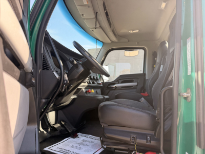 Truck cab interior view of a 2024 Kenworth T880 conventional daycab showing driver seat and dashboard elements.