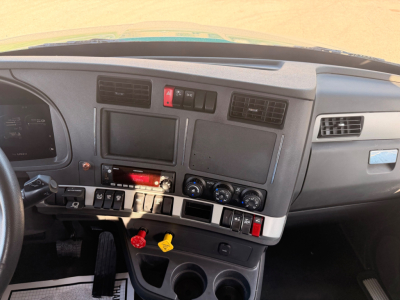 Kenworth T880 interior dashboard view showing center console with two blank screens, controls, climate dials, and cup holders.