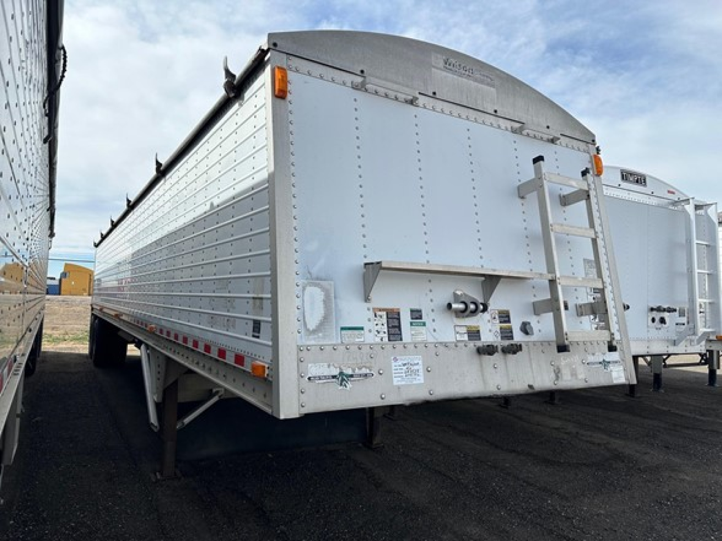 Trailer showing rear view of a white Wilson grain hopper trailer with ladder gate and inspection markings