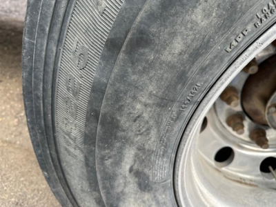 Wheel end of a Wilson grain trailer showing tire tread and lug nuts; partial rim and hub visible.