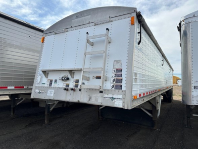 Trailer rear showing hopper grain trailer with ladder and rear doors, white exterior, reflective striping and warning decals.