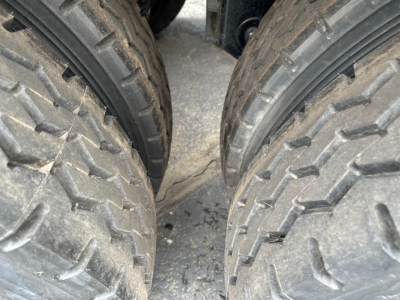 Dual rear tires of a trailer with tread pattern visible; close-up view undercarriage shows tire sidewalls and road grime.