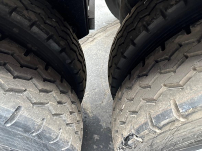 Dual large truck tires with rugged tread on a Jet Side Dump trailer, slight wear and road grime visible on asphalt.