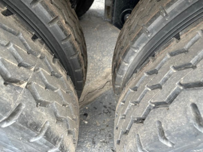 Dual rear wheels of a dump trailer with treaded tires; close-up view showing the wheel hubs and gaps between tires.