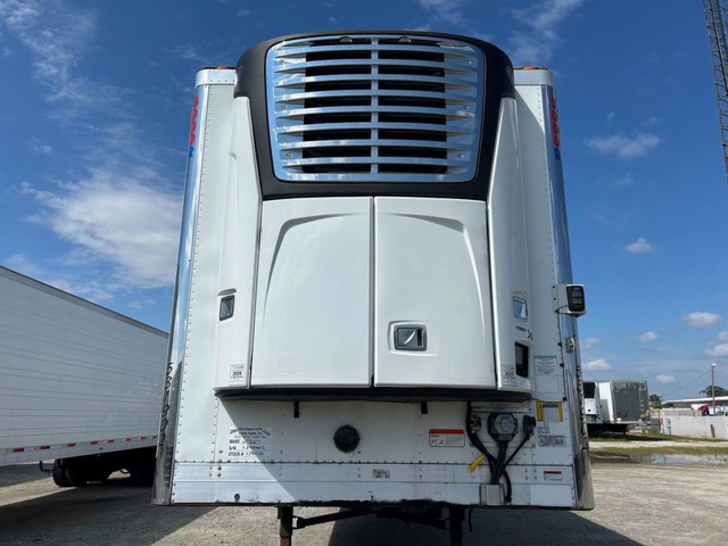 Truck trailer rear view showing Thermo King unit and doors; visible labels and hoses near lower right corner.