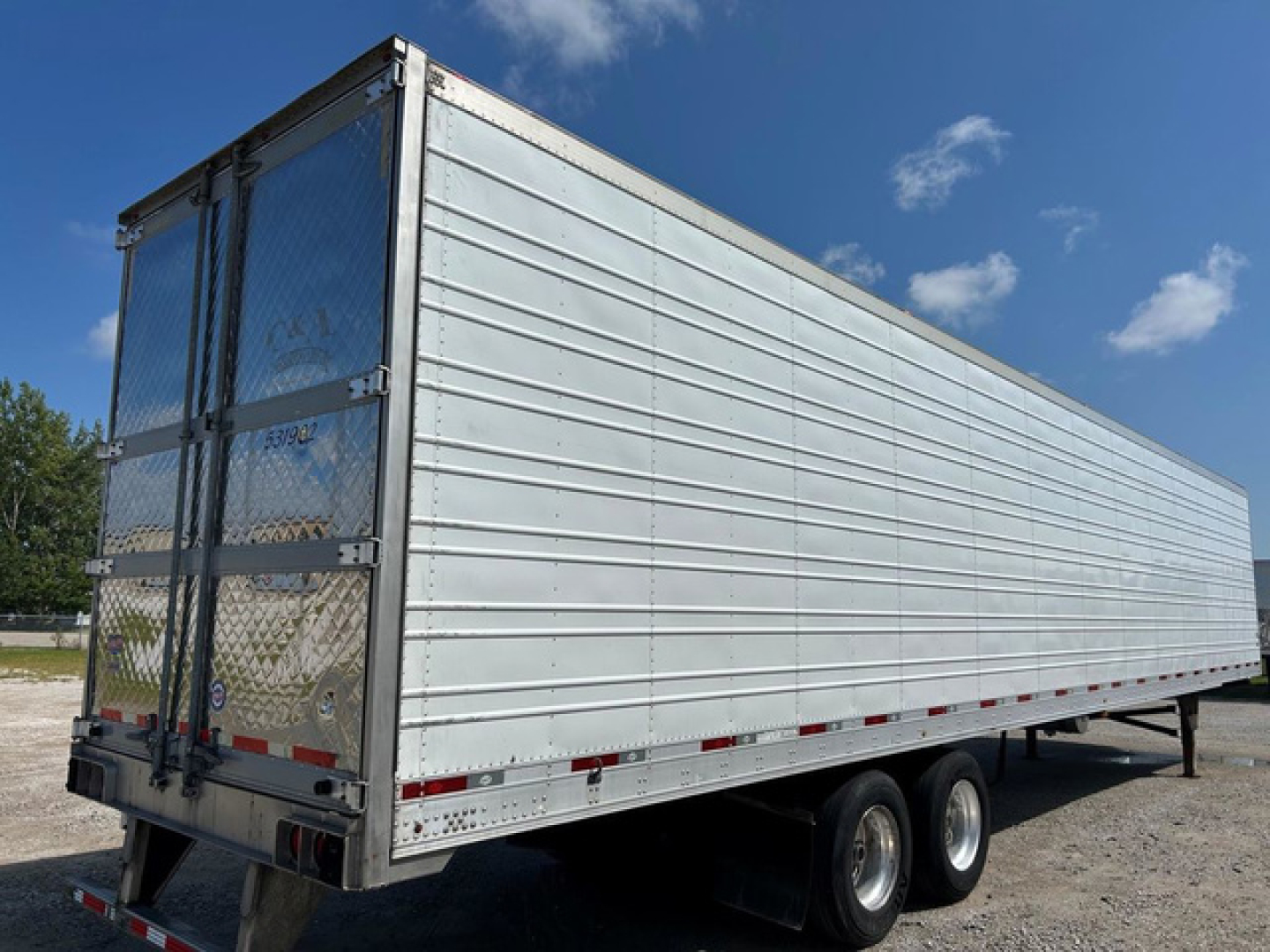 Trailer side view showing utility reefer trailer with aluminum panels and dual rear doors.