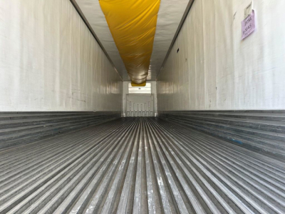 Trailer interior showing corrugated metal floor and ceiling with a yellow insulation duct along the top; back door visible at far end.