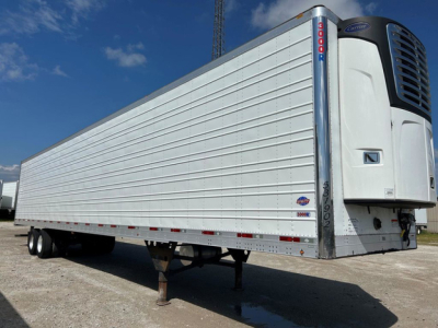 Refrigerated trailer showing Thermo King reefer unit at front, white corrugated sides, truck trailer with landing legs down.