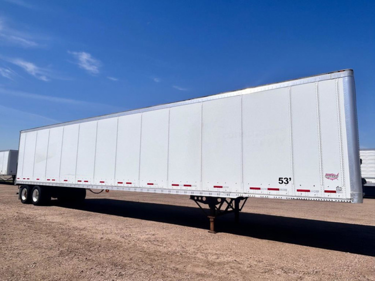 Trailer side view showing a white 53' Wabash van trailer with tandem axles and landing gear visible.