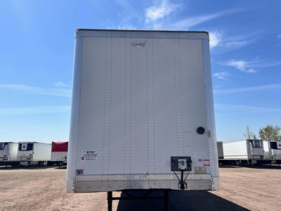Trailer rear showing vertical riveted panels and rear bumper, with a small access panel and hitch area visible.