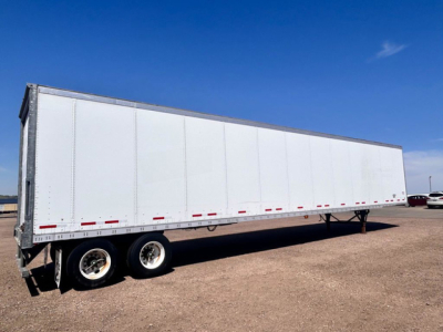 Trailer side view showing a white Wabash van trailer with dual rear axles and a long rectangular body.