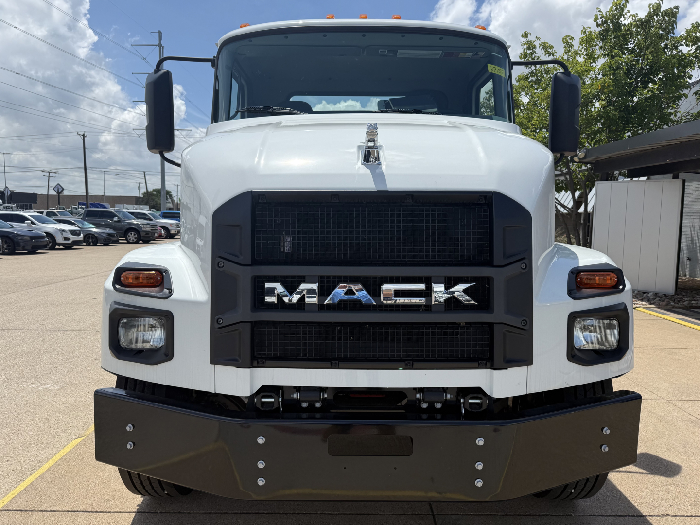 Front view of a white 2025 Mack MD6 truck showing large black grille with MACK lettering, headlights, and a heavy-duty front bumper.