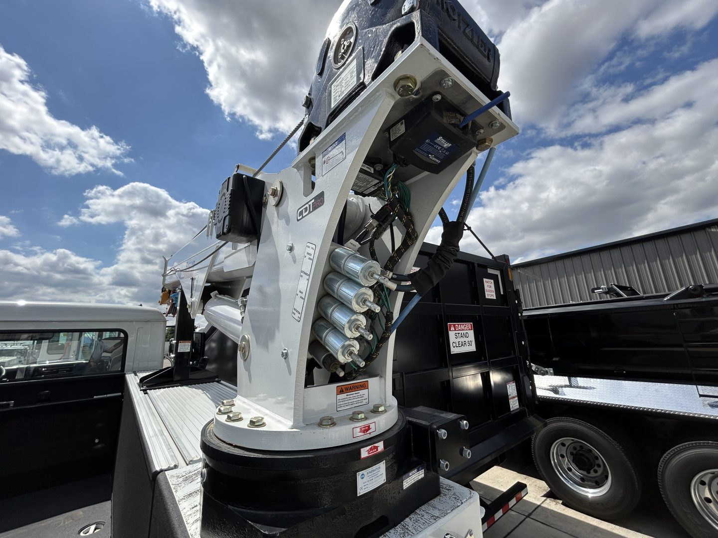Service/Utility truck equipment showing a hydraulic crane/boom with multiple cylinders and control levers mounted on white metal framework.