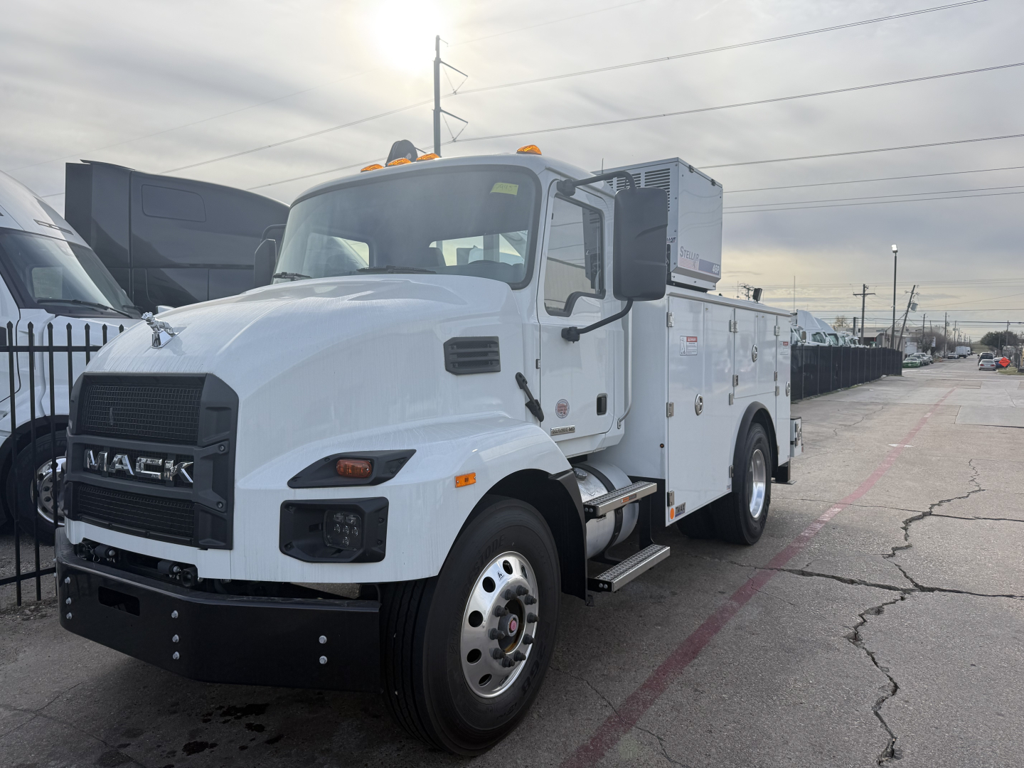 Front-left view of a white 2025 Mack MD6 service truck with utility compartments and equipment on a flatbed, VIN 1M2MDBAA6SS018367 visible in listing context.