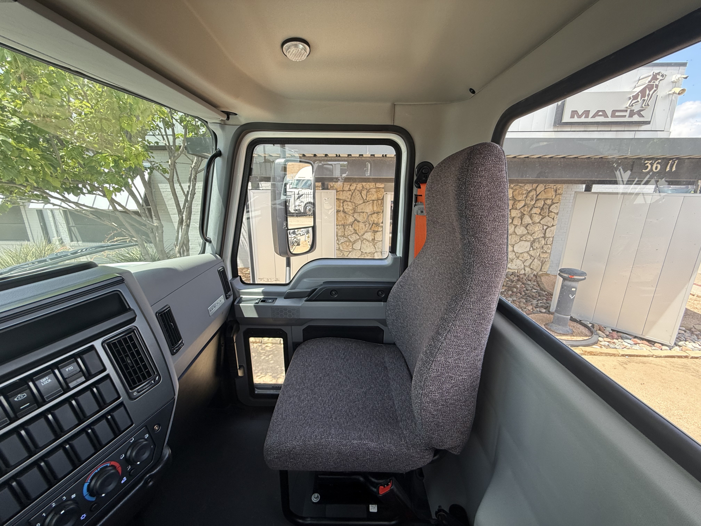 Truck cab interior view showing driver's seat, dashboard, and steering area with side window; no additional text visible.