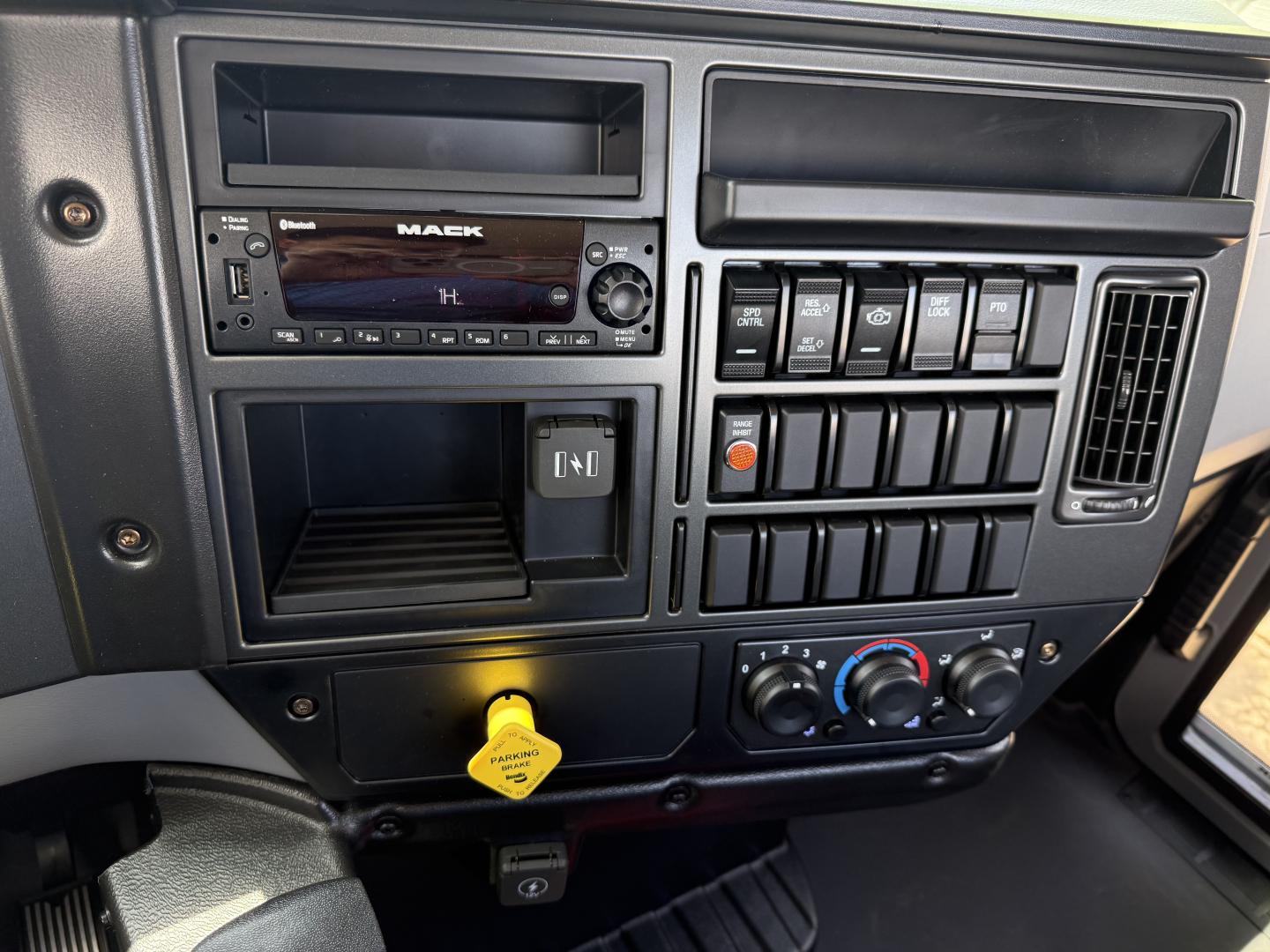 Dashboard of a 2025 Mack MD6 showing factory stereo, multiple switches, climate controls, and ignition area.