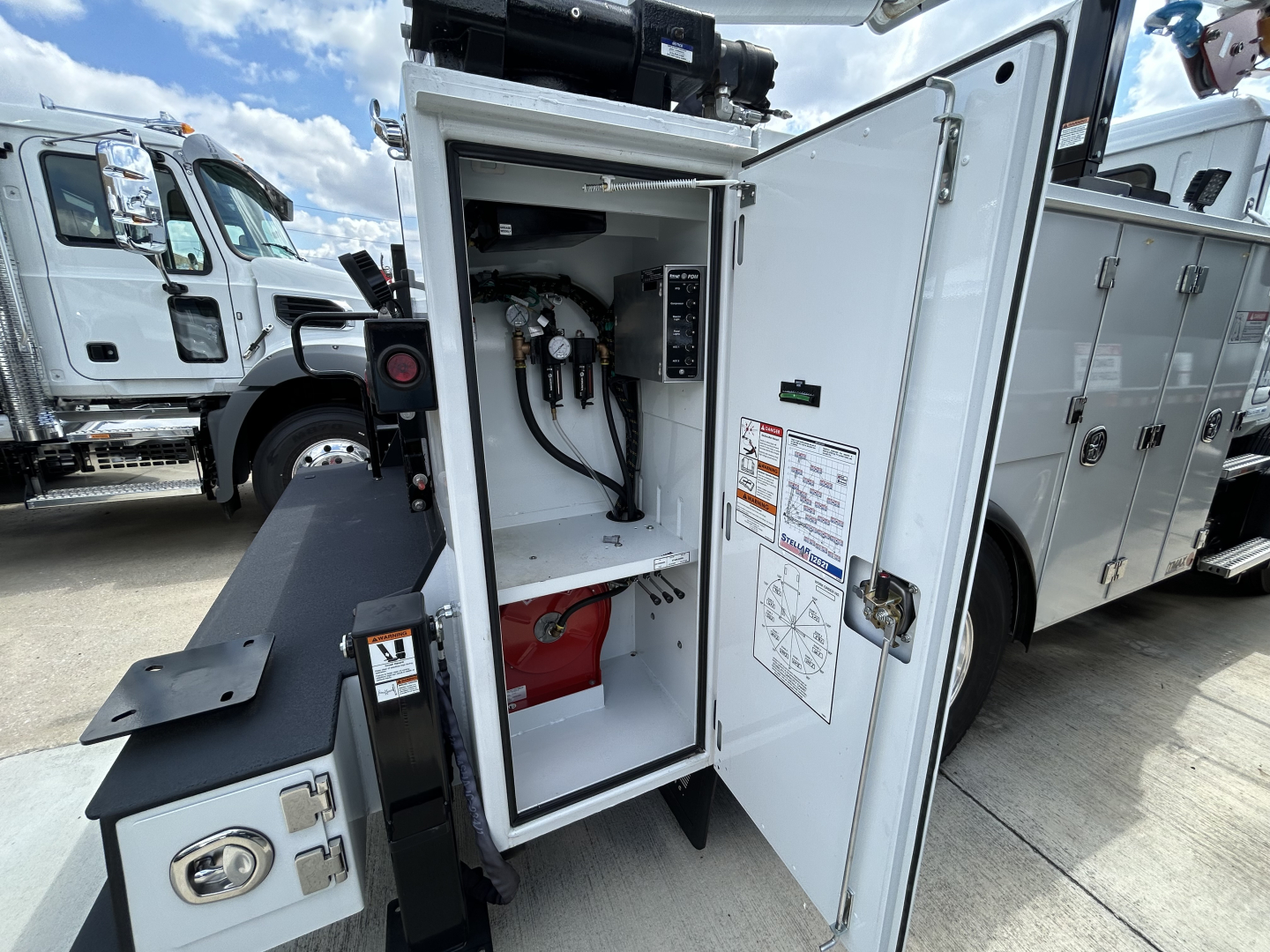 MD6 service truck cabinet open showing hydraulic/power components and hoses inside with warning label.
