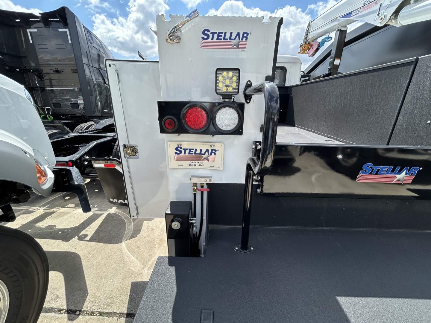 Mack MD6 chassis showing Stellar hydraulics control panel with circular red/white lights and a rectangular LED, dual display, and hook attachment.