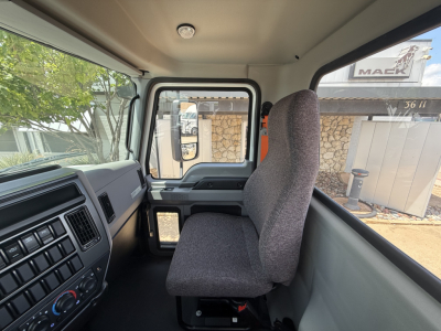 Truck cab interior view showing driver's seat, dashboard, and steering area with side window; no additional text visible.