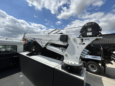 Mack MD6 truck bed with mounted hydraulic crane in service utility configuration showing crane base, hydraulic lines, and mounting hardware.